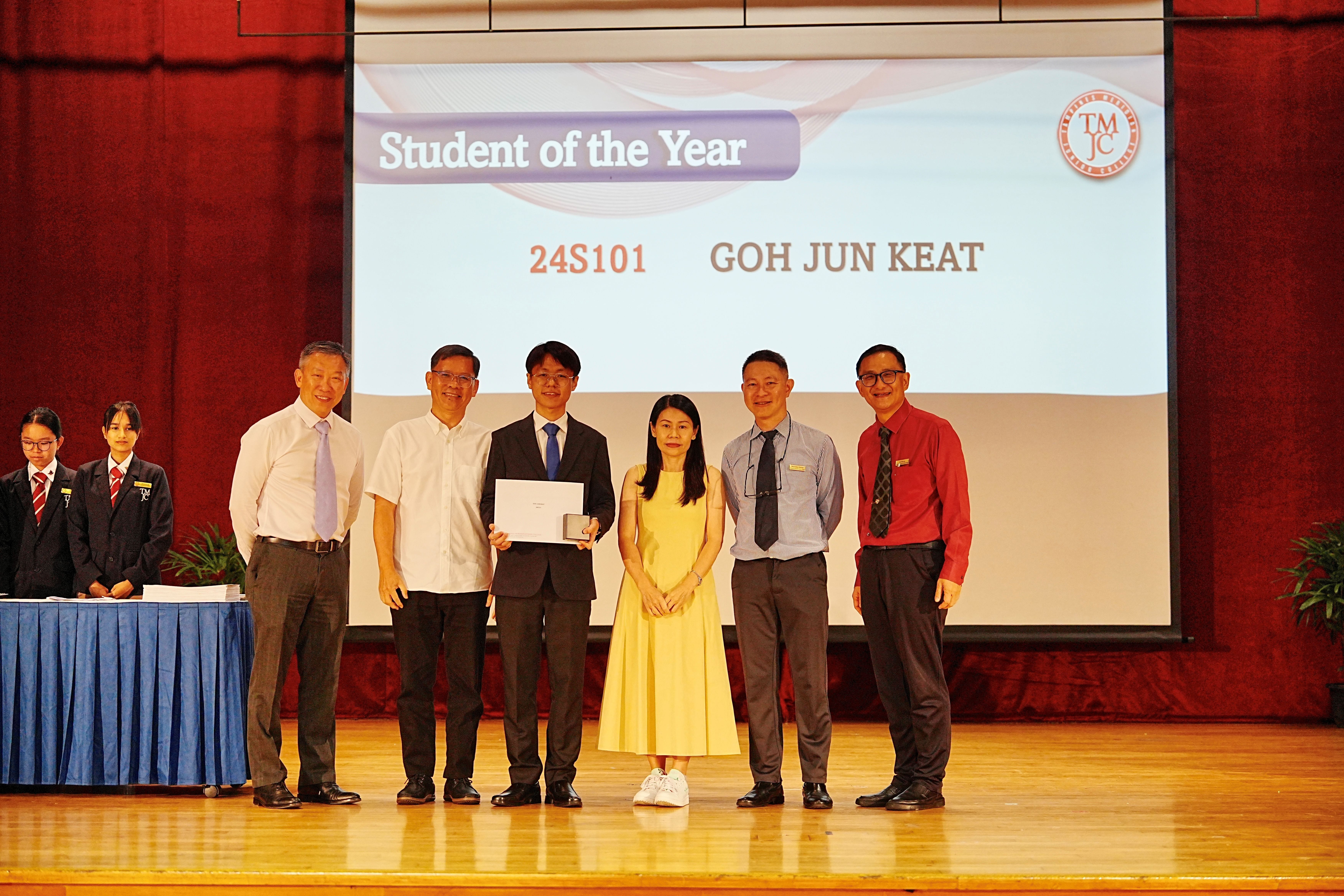 Student of the Year Goh Jun Keat from class 24S101 receiving his award on stage, flanked by teachers and school leaders.